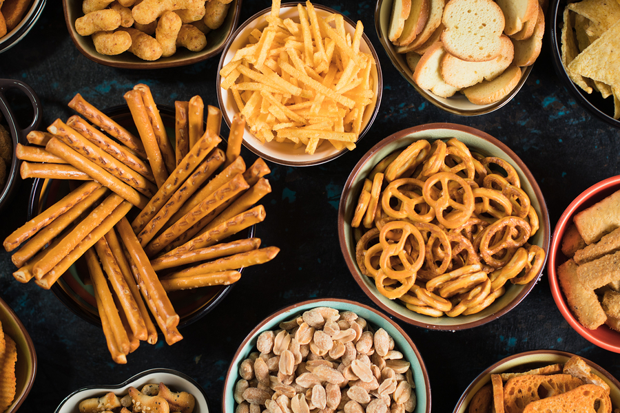 Salty snack including peanuts, potato chips and pretzels served as party food in bowls