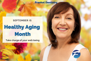 Healthy older woman smiling in front of trees in fall colors.